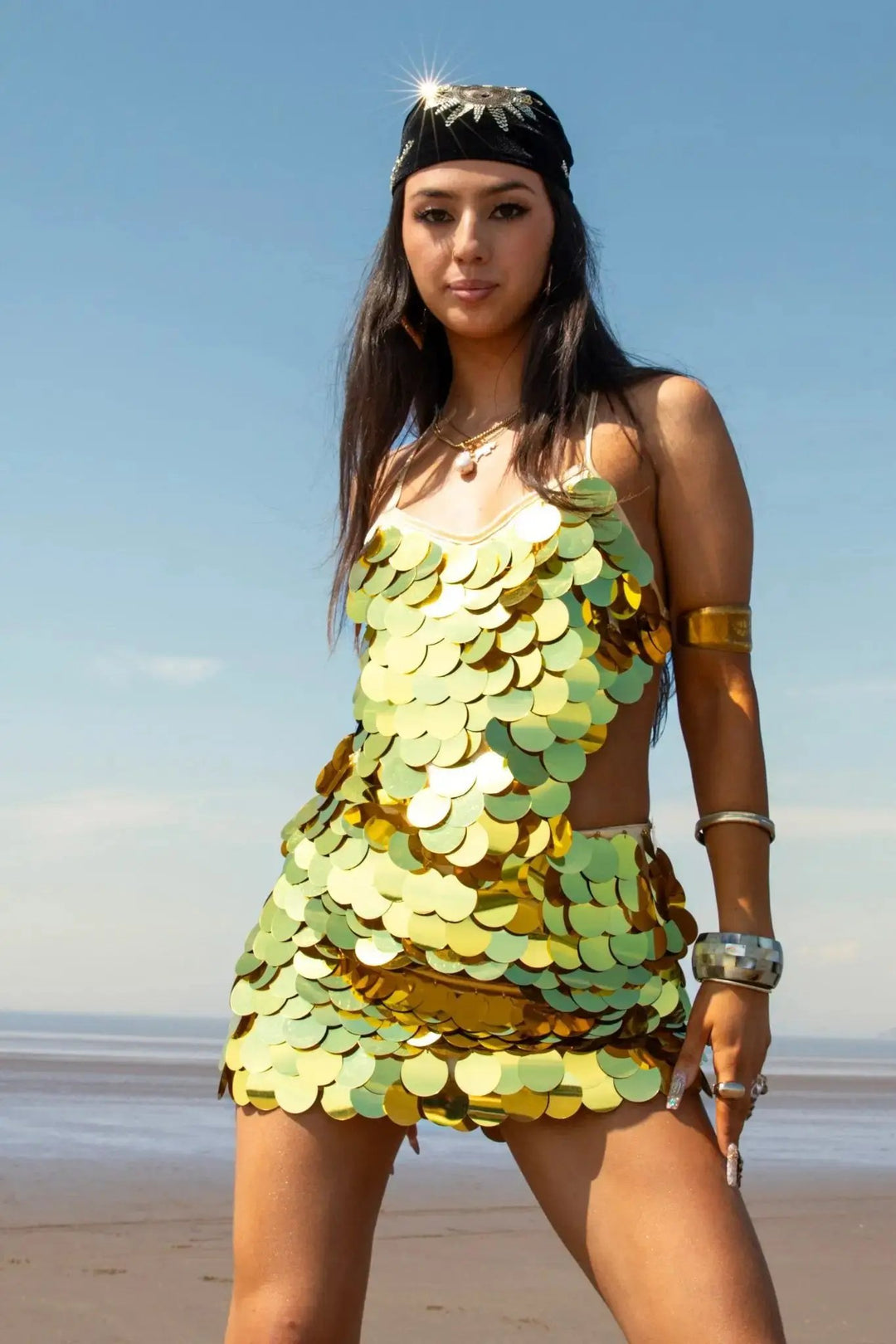 Belize Crop Top (Copy) in metallic green and gold sequins, styled for rave and festival wear on a beach background.